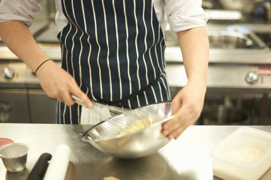 Mid section of male teenage catering student whisking in bowl at college