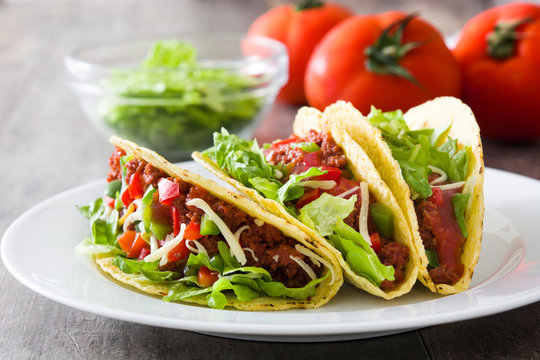Traditional Mexican tacos with meat and vegetables on wooden background
