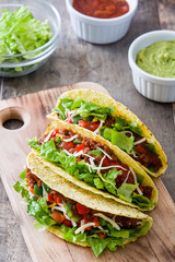 Traditional Mexican tacos with meat and vegetables on wooden background
