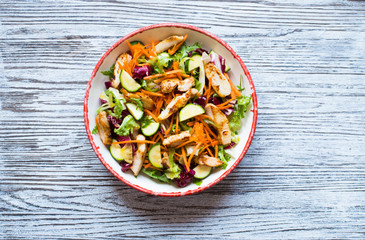 Salad of chicken breast with zucchini and cherry tomatoes, on a wooden background