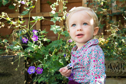 Blue eyed baby girl looking up in garden