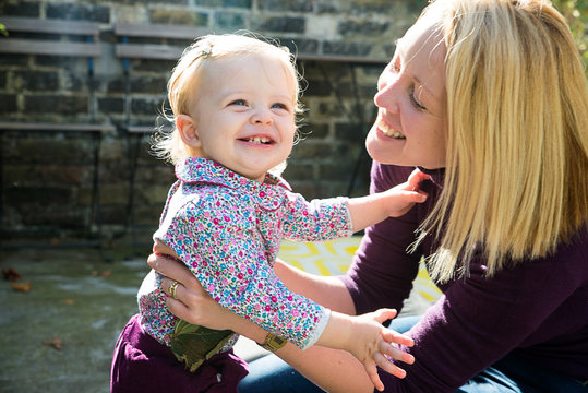 Mid adult woman playing with baby daughter in garden