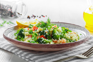 Delicious healthy meal made of couscous, broccoli and other vegetables on a rustic wooden table. Traditional eastern food. Close-up shot.