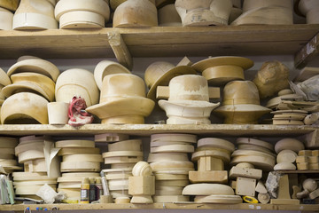 Stacked shelves with wooden moulds for headwear in workshop