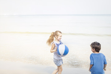 girl and boy playing water ball on the beach