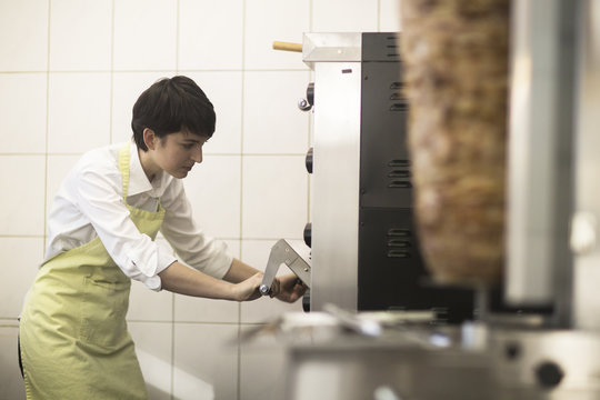 Young woman cooking food in fast food shop
