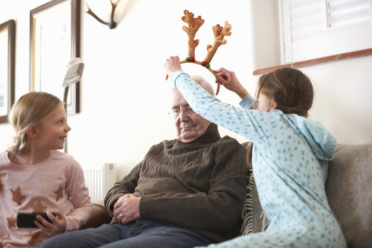 Sisters putting reindeer antlers on sleeping grandfather