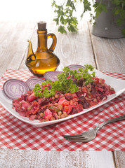 Russian beetroot salad vinaigrette White plate on checkered napkin on wood background