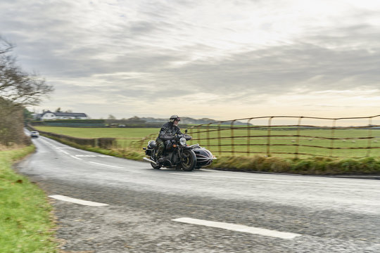 Senior man and grandson riding motorcycle and sidecar on rural road
