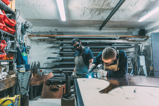 Metalworker cutting copper with welding torch in forge workshop