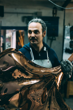 Metalworker holding copper product in forge workshop