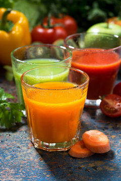 assortment of fresh vegetable juices on a blue background, vertical, closeup