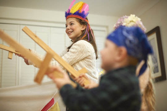 Dressed up boy and two sisters having sword fight