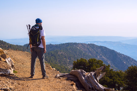 Bearded man, traveler with backpack on the mountain trail