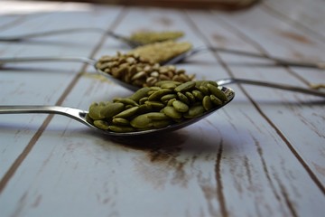 Seeds in spoons on white wood background