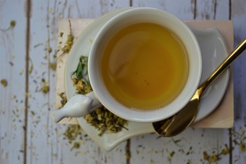 Isolaed cup of herbal tea with dried herbs and gold spoon