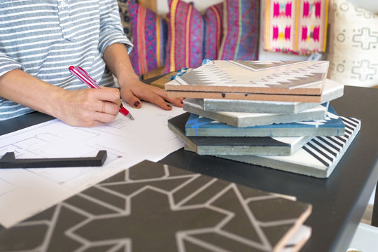 Mid section of female interior designer drawing designs at desk in retail studio