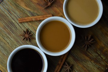 3 coffee cups on wood table with cinnamon sticks and star anise 