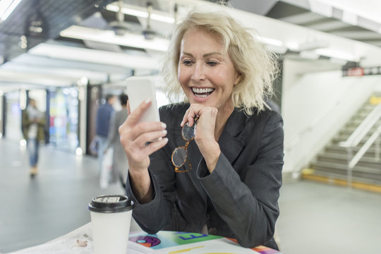 Mature woman looking at smartphone in shopping mall cafe