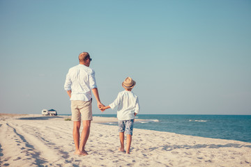Father and son walks on deserted sea beach not far from their auto camp