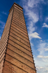 Fototapeta na wymiar Old brick chimney near sky clouds.