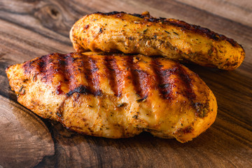 Grilled chicken breast on wooden cutting board
