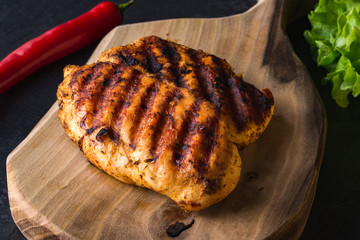 Grilled chicken breast on wooden cutting board