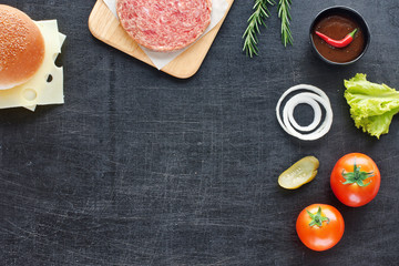 Minced beef, sesame bun, cheese, tomato, lettuce, onion, pickle, hot BBQ sauce, chili. Home handmade hamburger. Black background. Space for text.