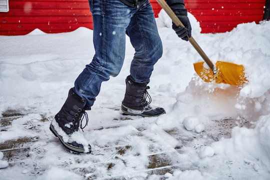 Man shovelling snow from pathway, low section