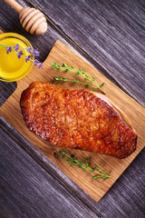 Duck breast, lavender honey and thyme, served on chopping board. View from above, top studio shot