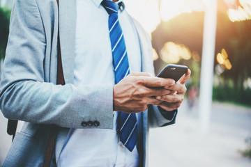 Closeup shot of male hands using modern smartphone outdoors, professional businessman checking his documents and e-mail during a break, successful manager analyzing market sales via cellphone