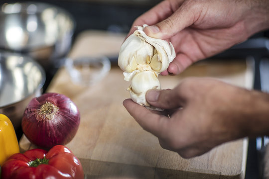 Chef peeling fresh garlic, close-up