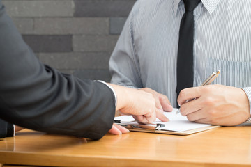 Two business partners signing contract in document