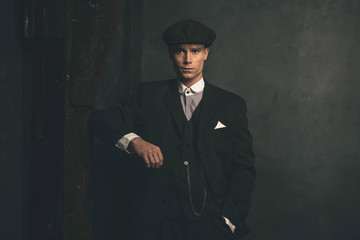 Retro 1920s english gangster wearing suit and flat cap.
