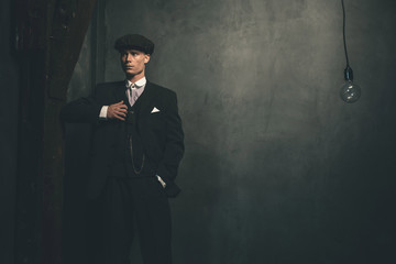 Retro 1920s english gangster wearing suit and flat cap.