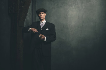 Retro 1920s english gangster standing with cigarette.