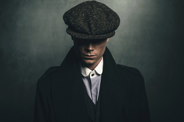 Mysterious portrait of retro 1920s english gangster with flat cap. - obrazy, fototapety, plakaty