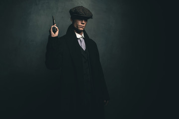 Dangerous retro 1920s english gangster standing with gun.