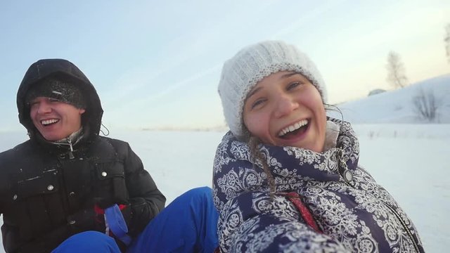 Happy young couple are sledding in the mountain through the ssnow in slow motion on sunny day and recording themself on video. 1920x1080