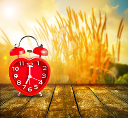 Red clock mark on 7 o'clock put on wooden tabletop with abstract blurred on fresh green nature...