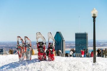 Snowshoes in snow with Montreal skyline in the distance