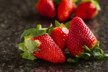 Fresh picked imperfect strawberries on marble surface
