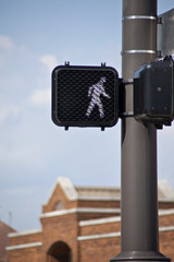Electronic crosswalk sign surrounded by blue sky and brick buildings.