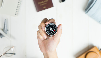 Explorer holding compass surrounded by travel accessories © junce11