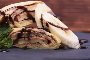crepe with banana and chocolate on round slate stand