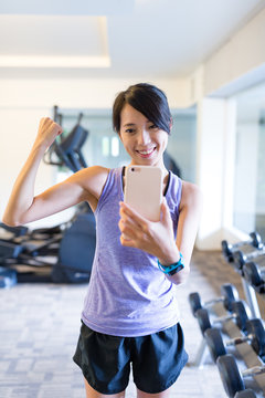 Sport Woman taking selfie in front of mirror in gym