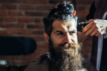 Bearded man with beard getting haircut by hairdresser at barbershop