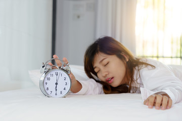 Sleepy woman trying turn off alarm clock in the morning.