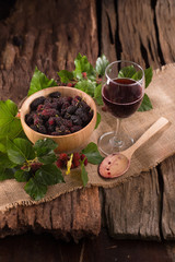 Mulberry berries in a wooden cup on a wooden background