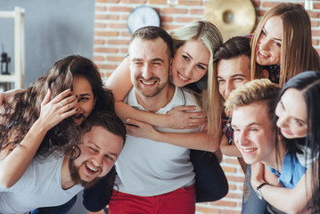 Group portrait of multi-ethnic boys and girls with colorful fashionable clothes holding friend  posing on a brick wall, Urban style people having fun, Concepts about youth  togetherness lifestyle